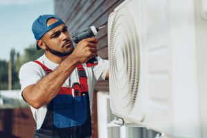 Repairman in uniform installing the outside unit of air conditioner