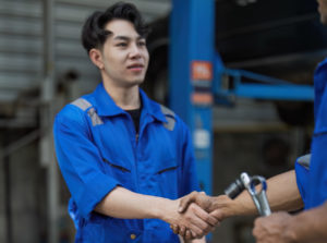 Two car mechanic team shaking hand at automobile service center. Repair service concept. Car repair and maintenance. Car mechanic working at automotive team service center